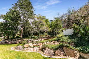 Terraced landscape featuring natural rock retaining walls, mature trees, and lush ground cover