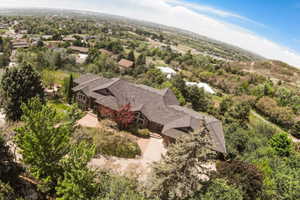 Expansive property featuring a multi-level roofline, extensive natural landscaping, a brick paver driveway, and a natural wood-sided exterior