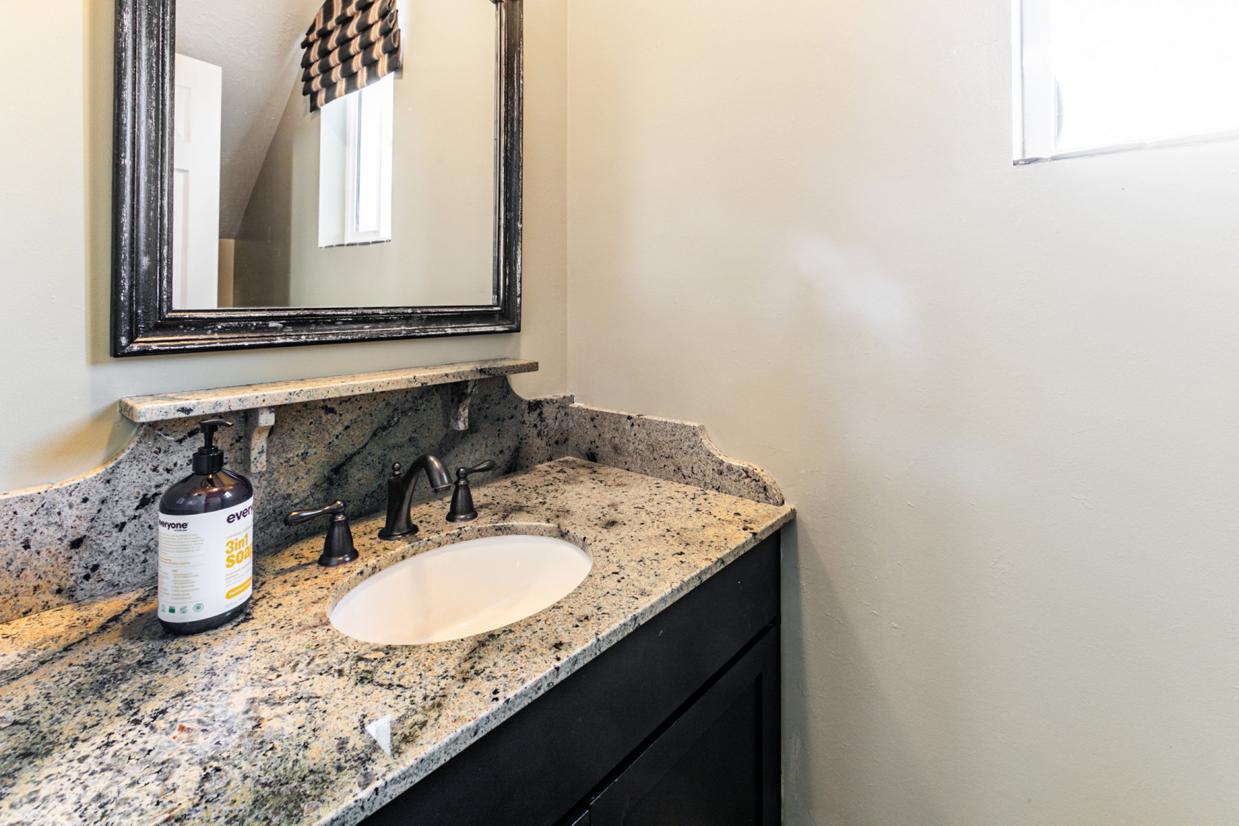 Granite countertop with integrated oval sink and dark bronze faucet