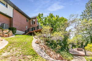 Rear exterior featuring a brick facade and a multi-level wooden deck