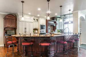 Spacious kitchen island with seating, featuring a stone-finish countertop, dark wood cabinetry, and recessed lighting