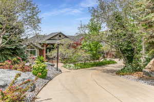 Curved concrete driveway leading to a brick and stone facade residence with an arched entry and a dark shingle roof