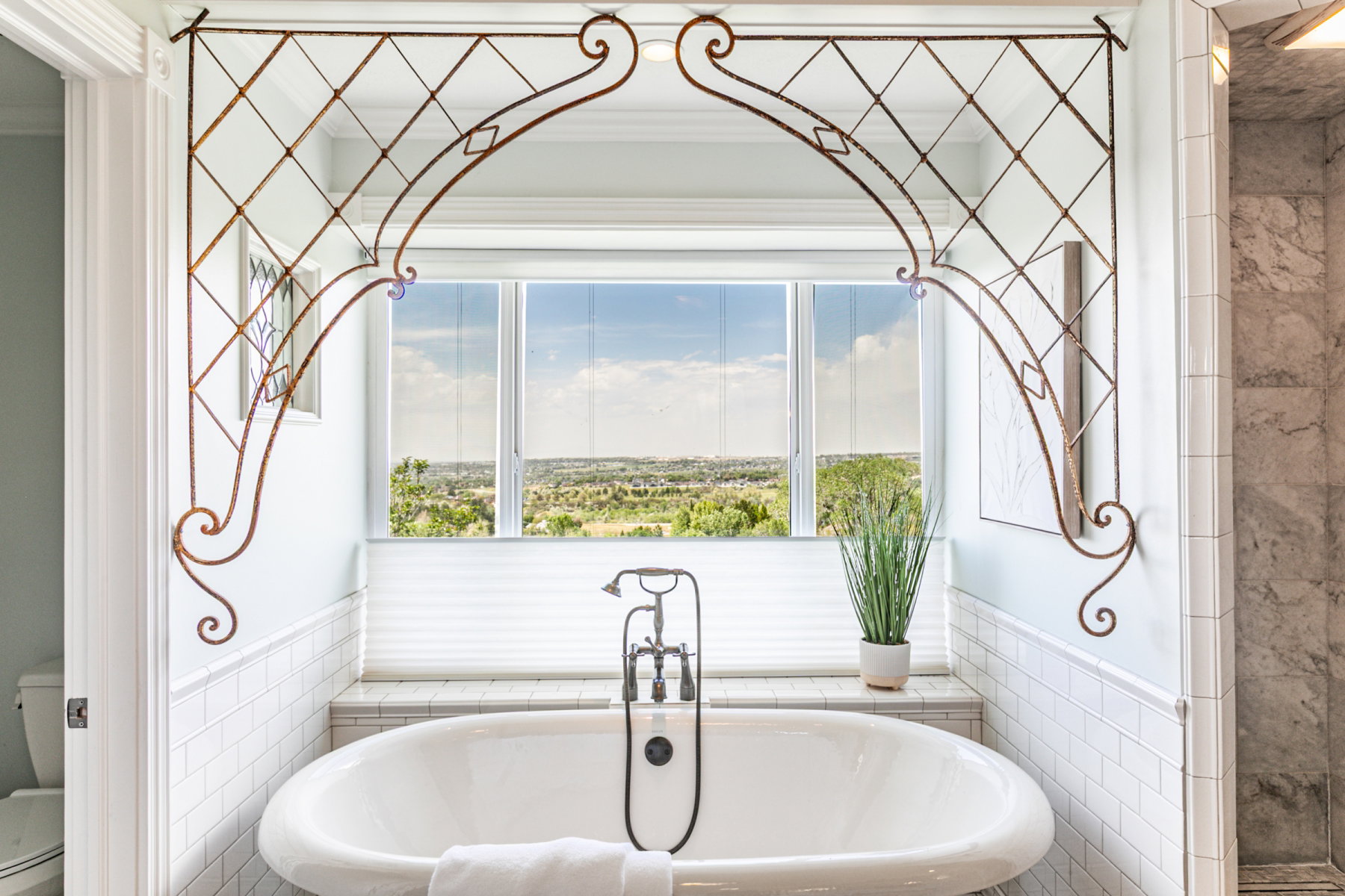 Freestanding soaking tub with a floor-mounted faucet and handheld showerhead