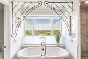 Freestanding soaking tub with a floor-mounted faucet and handheld showerhead
