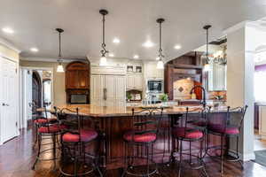 Kitchen featuring a large island with a stone countertop, dark wood-finish cabinetry, and three pendant lights