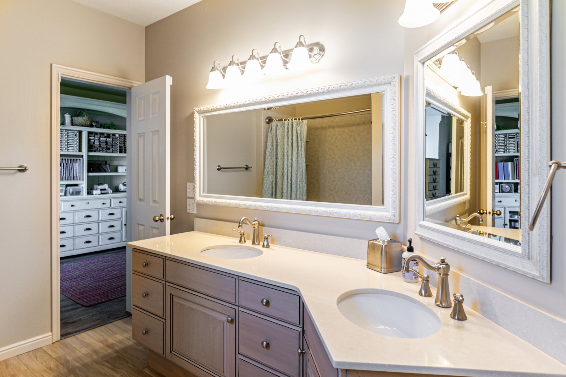 Bathroom vanity with dual sinks, light-toned countertops, and brushed nickel hardware