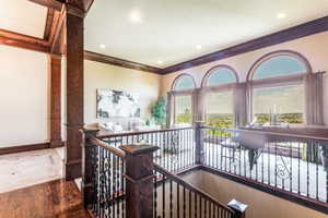 Upper-level landing featuring a grand staircase with dark wood newel posts and wrought iron balusters