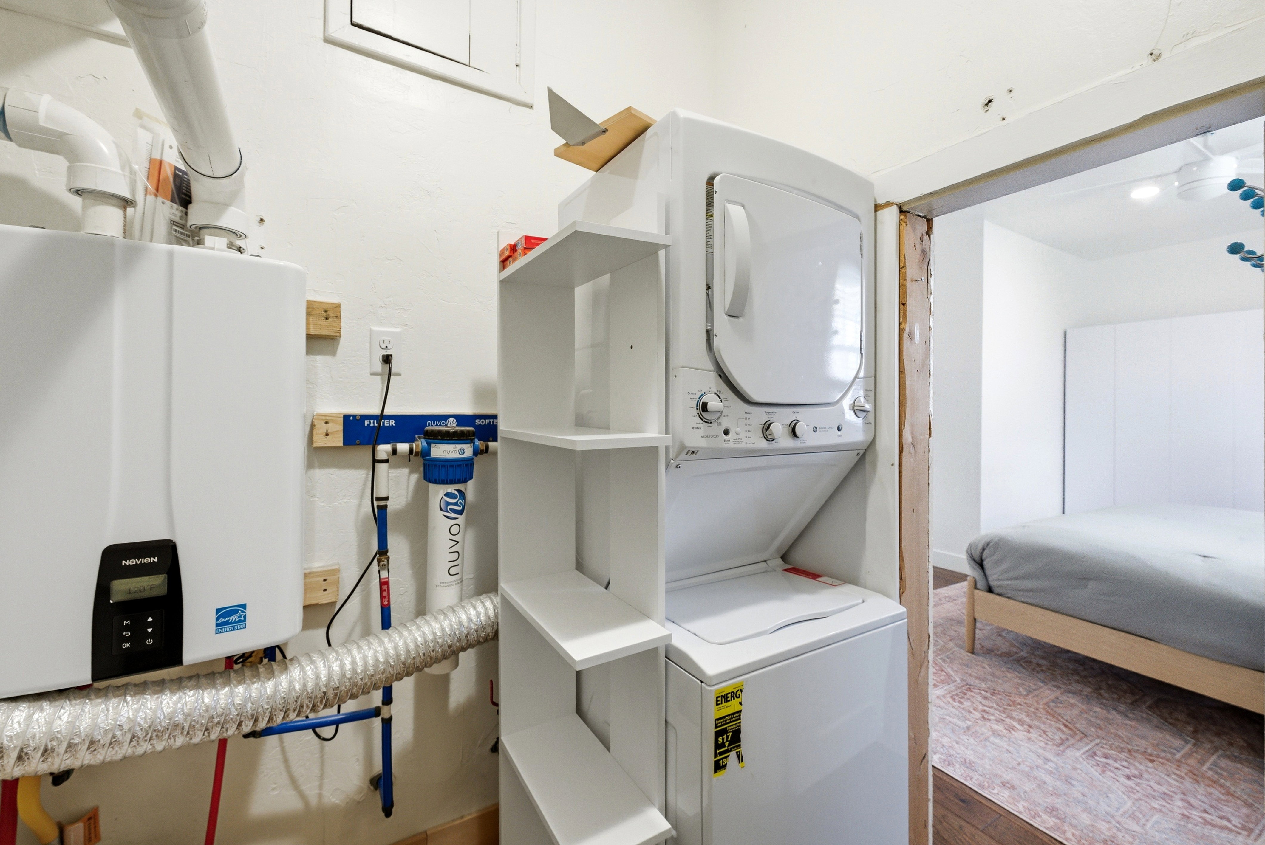 Utility area featuring a tankless water heater, water filtration system, and a white stacked washer and dryer