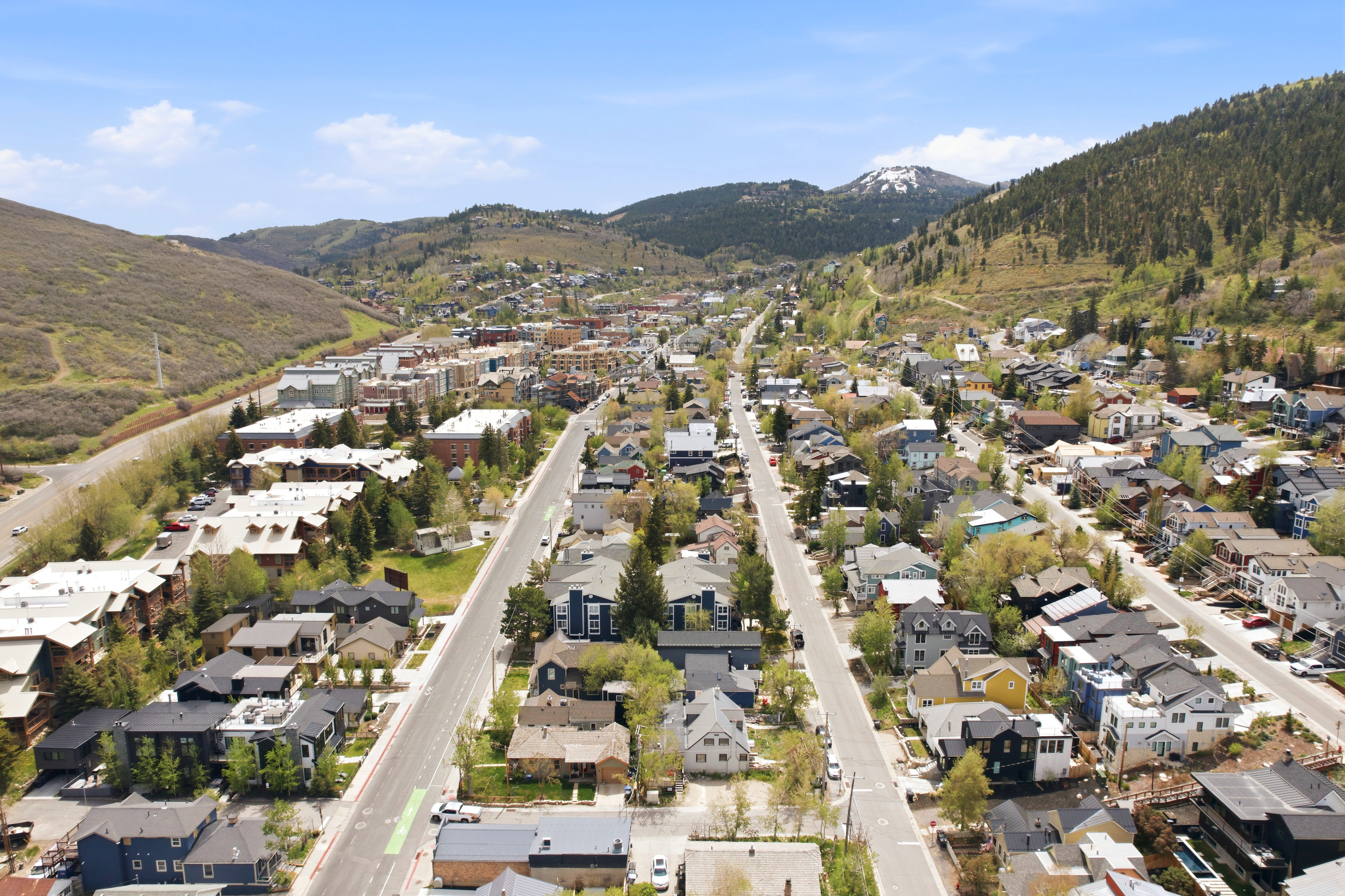 Aerial perspective showcasing a mountain town with residential and commercial properties nestled within a valley