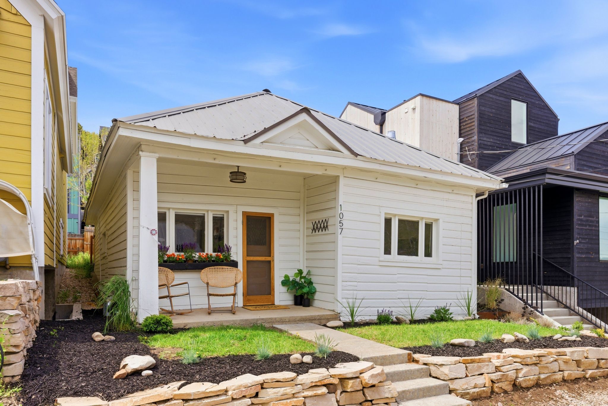 Single-story residence featuring white siding and a metal roof