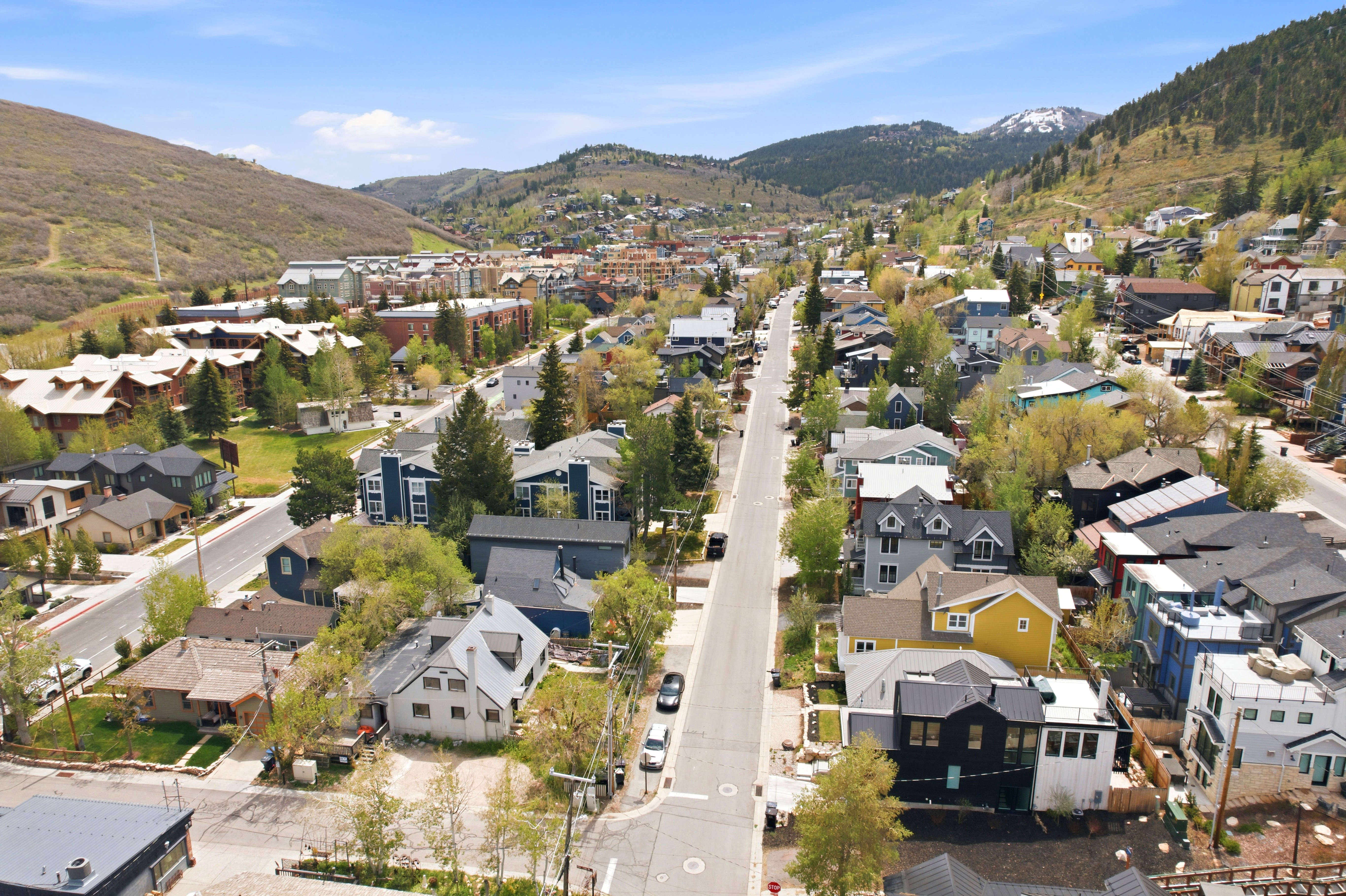Aerial perspective showcasing a residential area with diverse architectural styles, surrounded by mountainous terrain