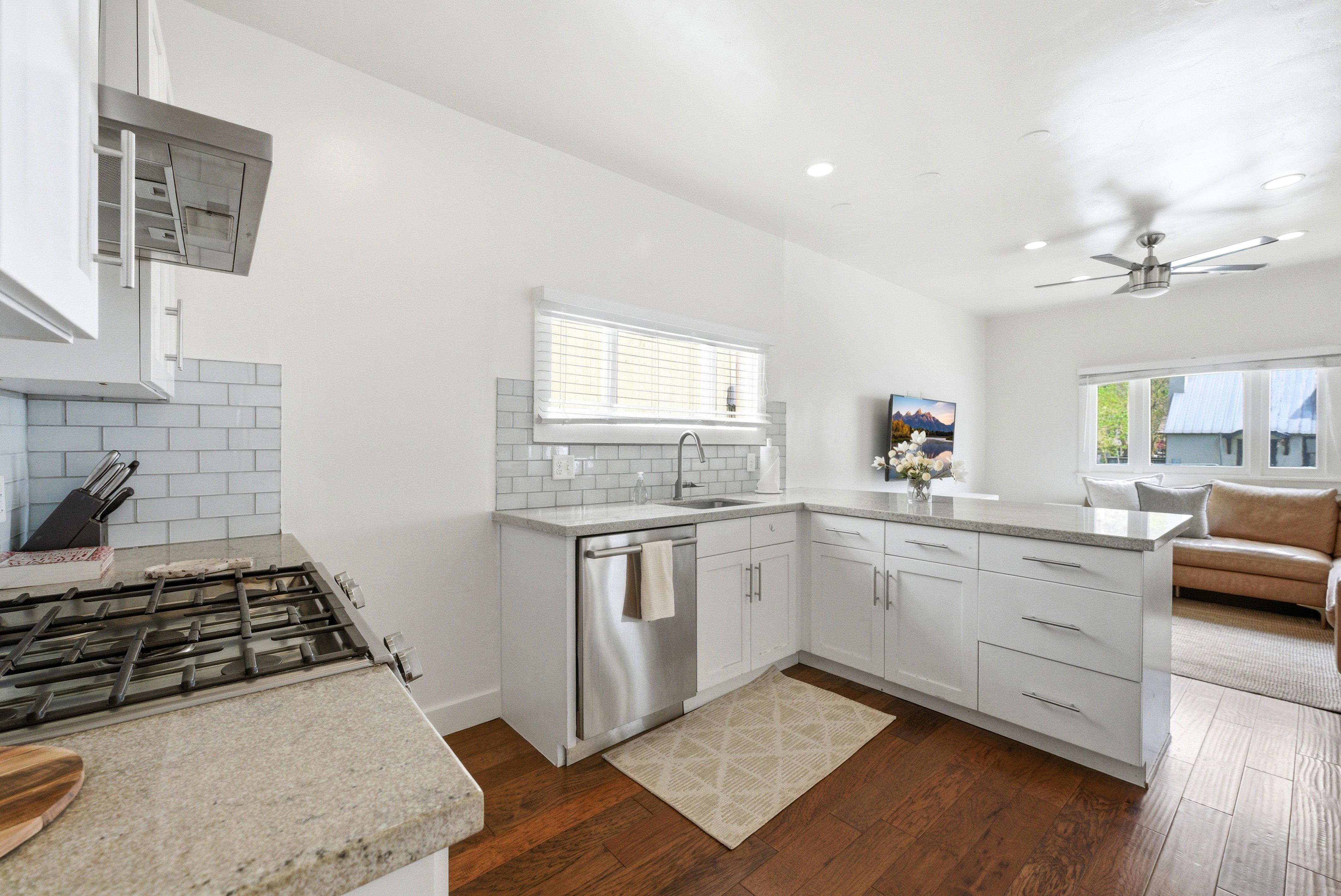 Open-concept kitchen featuring white cabinetry, light-toned countertops, and a subway tile backsplash