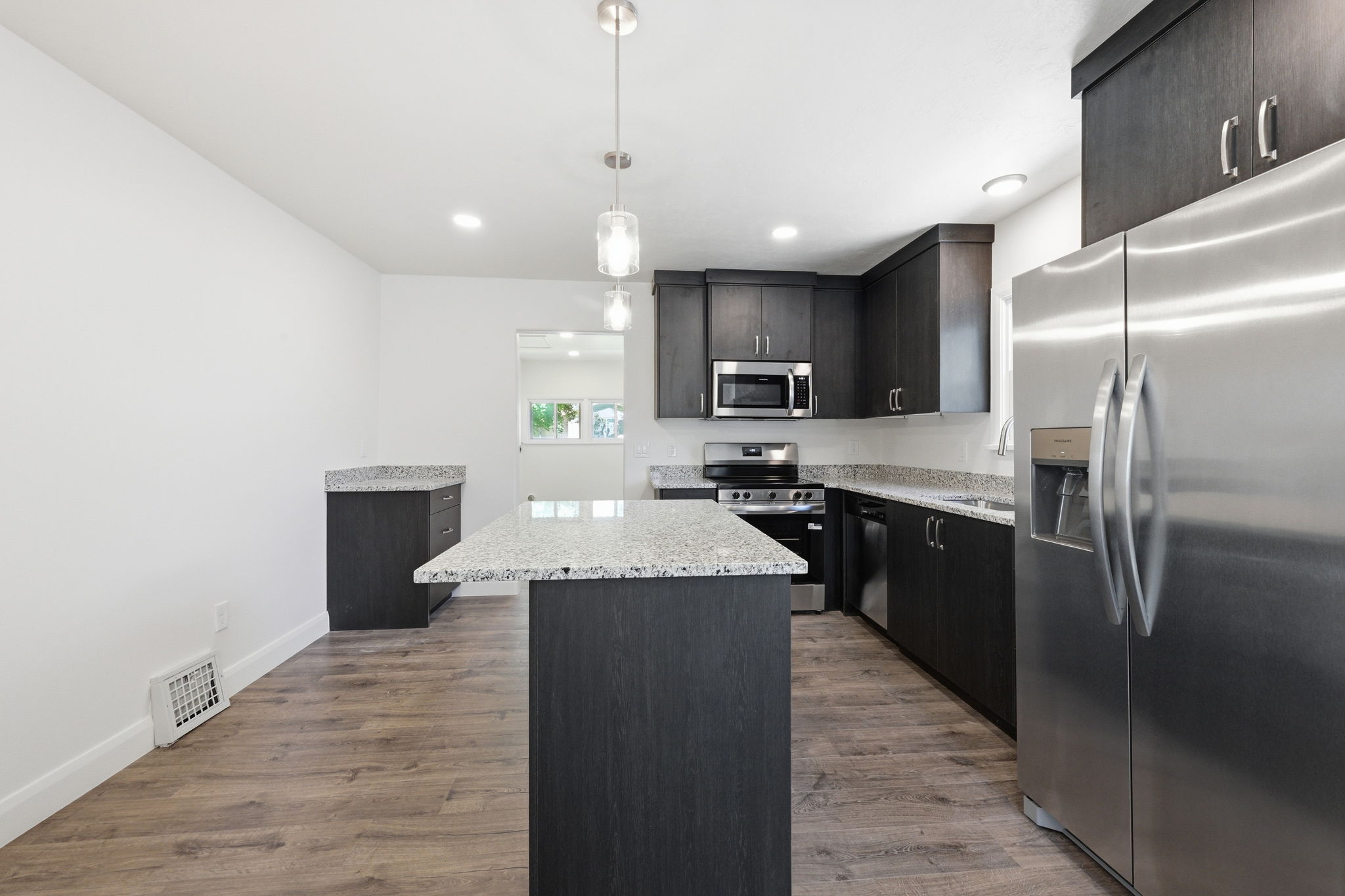 Kitchen featuring dark wood-finish cabinetry, light-toned countertops, and stainless steel appliances