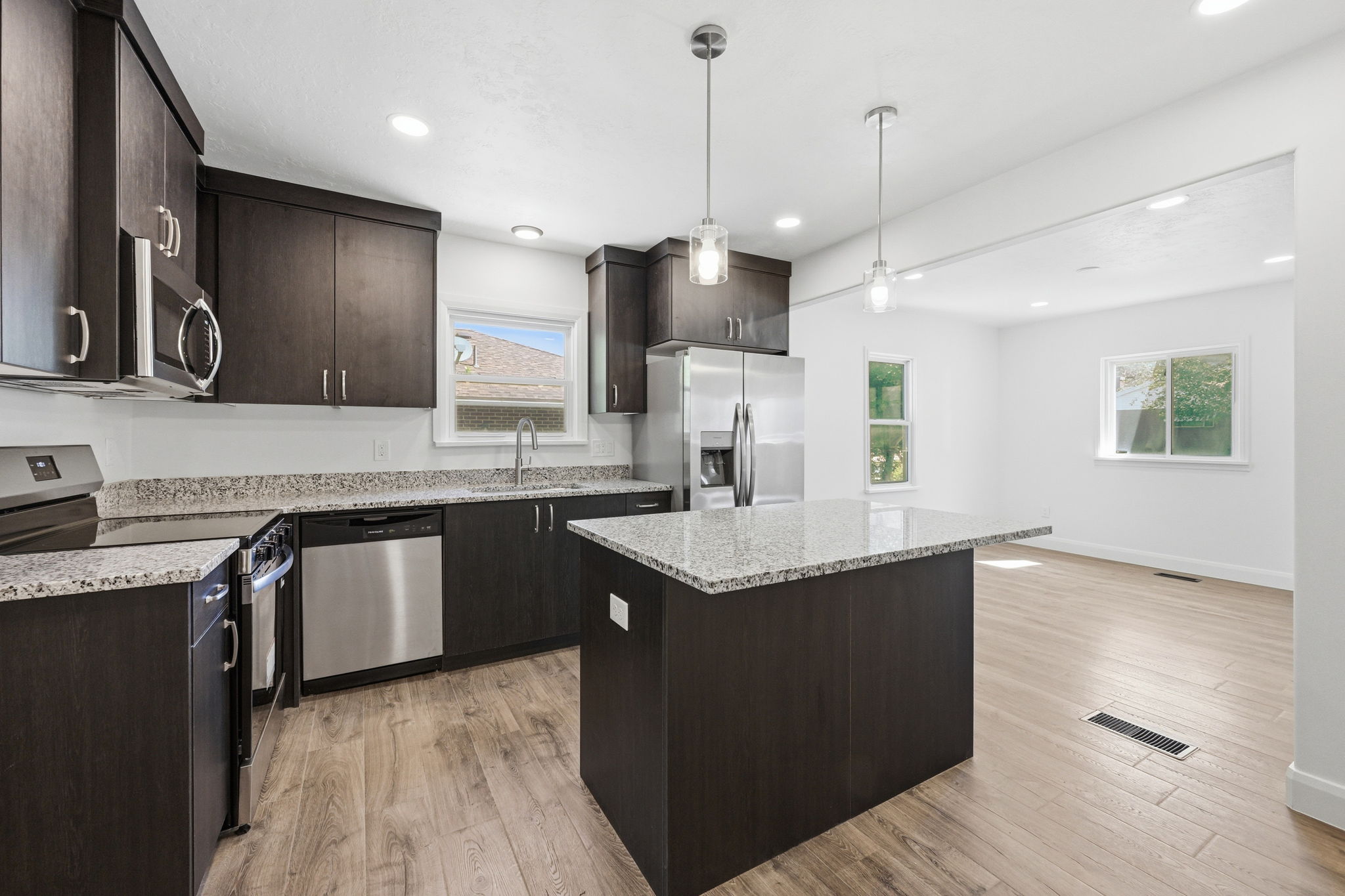 Modern kitchen featuring dark wood-finish cabinetry, stainless steel appliances, and light-toned countertops