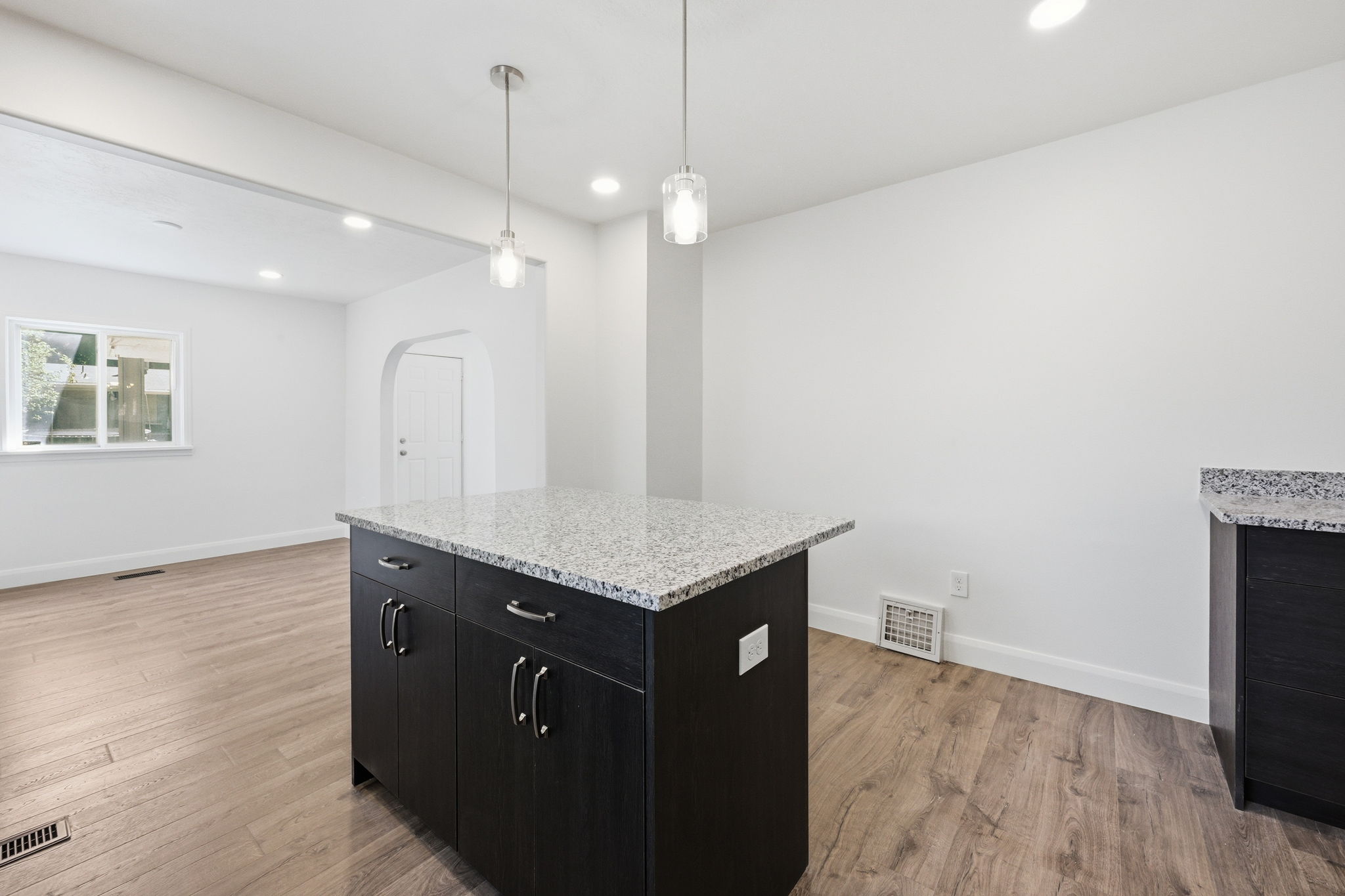 Kitchen island with a light-toned stone countertop and dark cabinetry