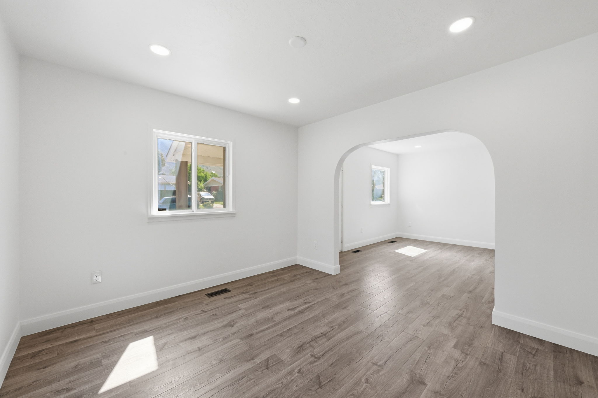 Expansive interior space featuring wood-finish flooring, recessed lighting, and a white color palette