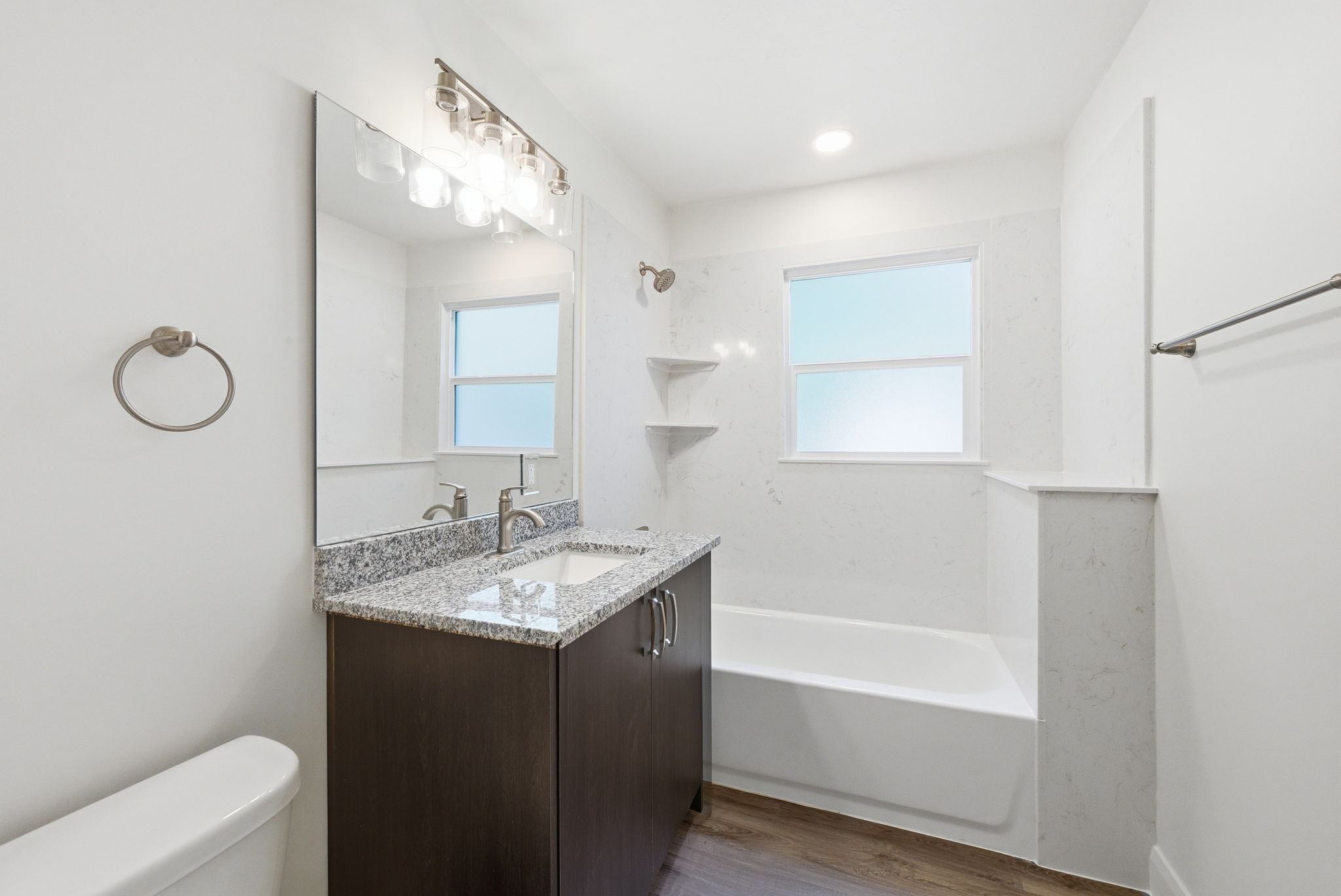 Full bathroom featuring a dark wood-finish vanity with a granite countertop, undermount sink, and brushed nickel fixtures