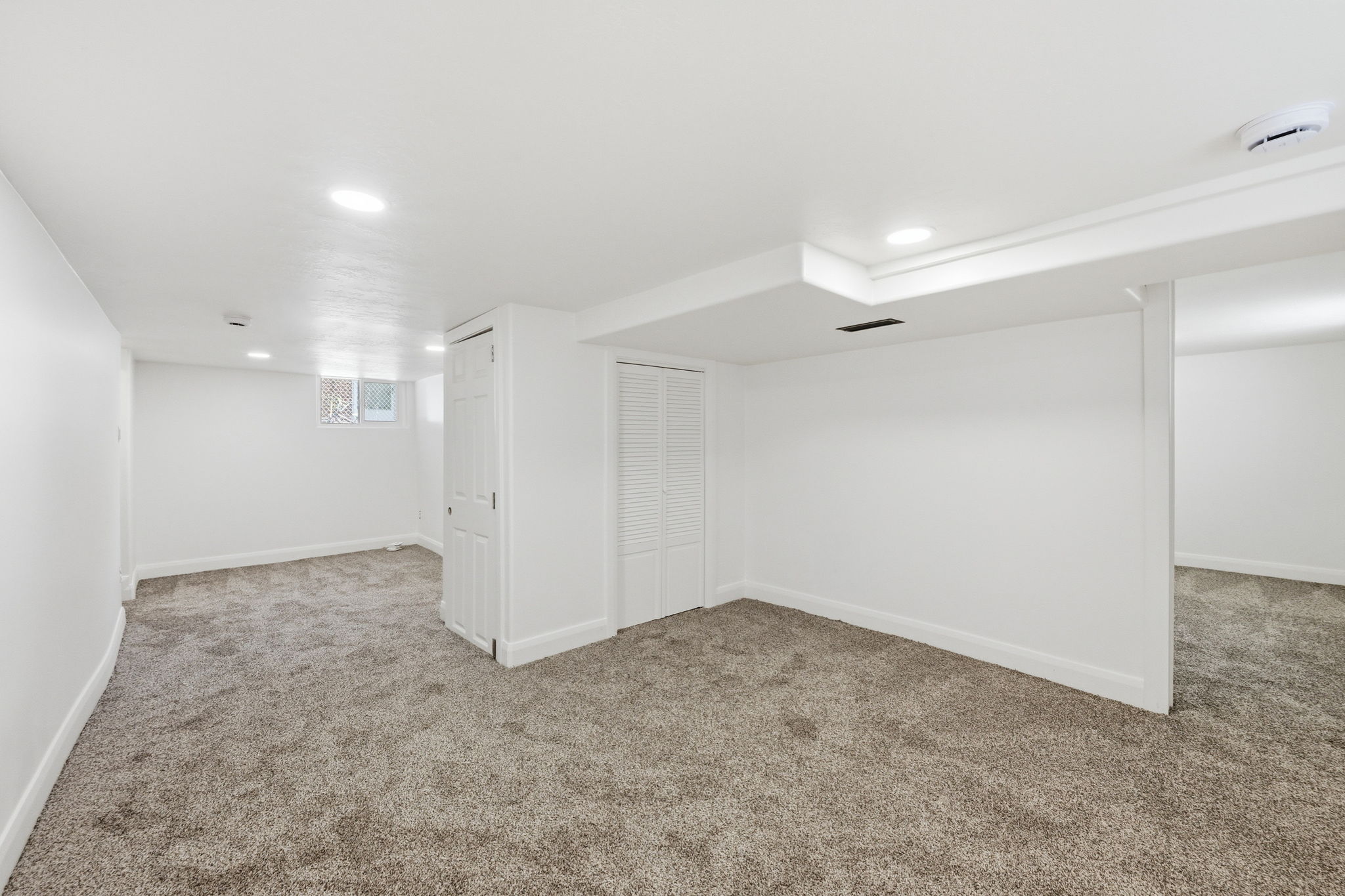 Spacious interior featuring neutral carpeting, white walls, recessed lighting, and white trim