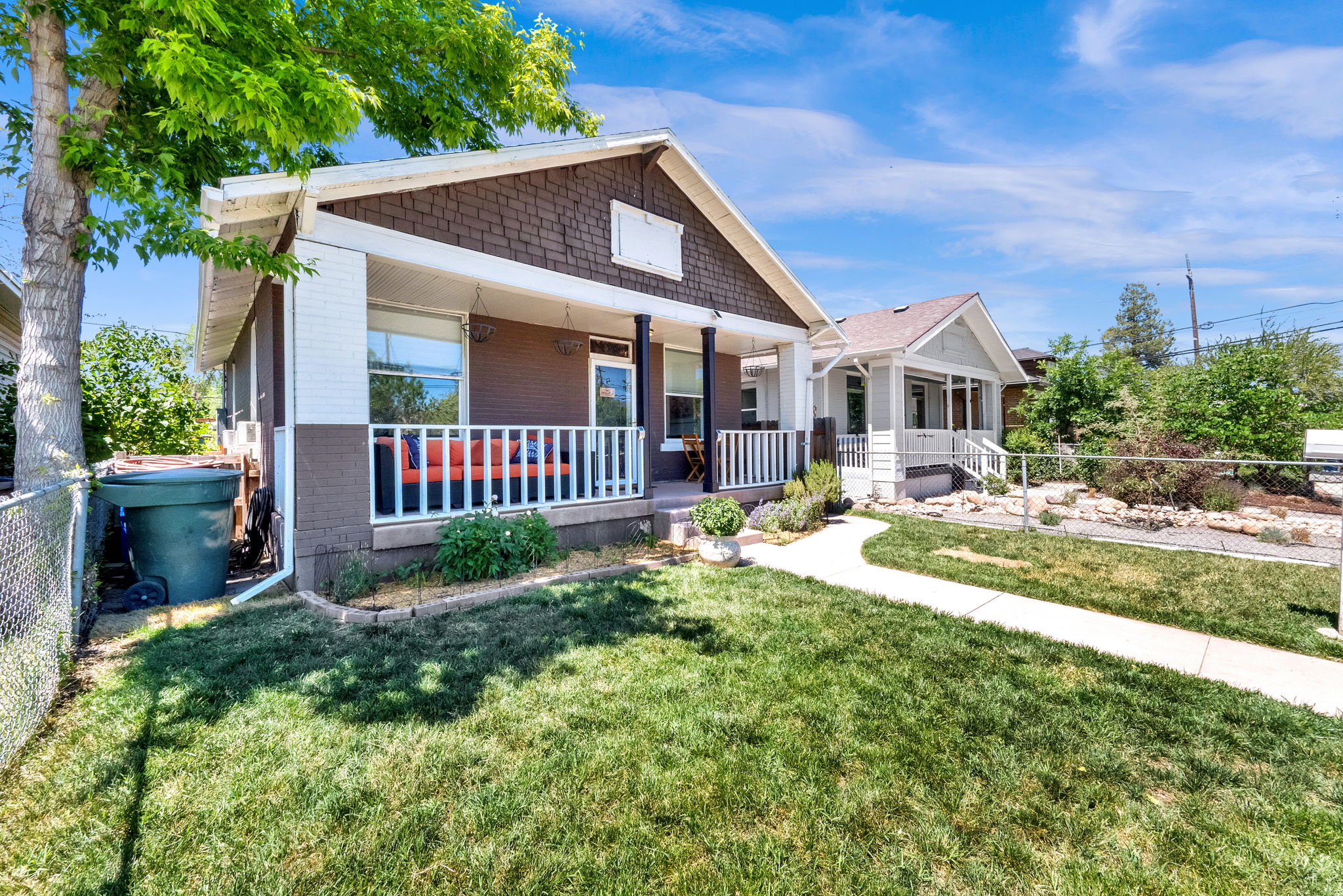 Charming bungalow exterior featuring a covered front porch with white railing, a manicured front lawn, and a paved walkway