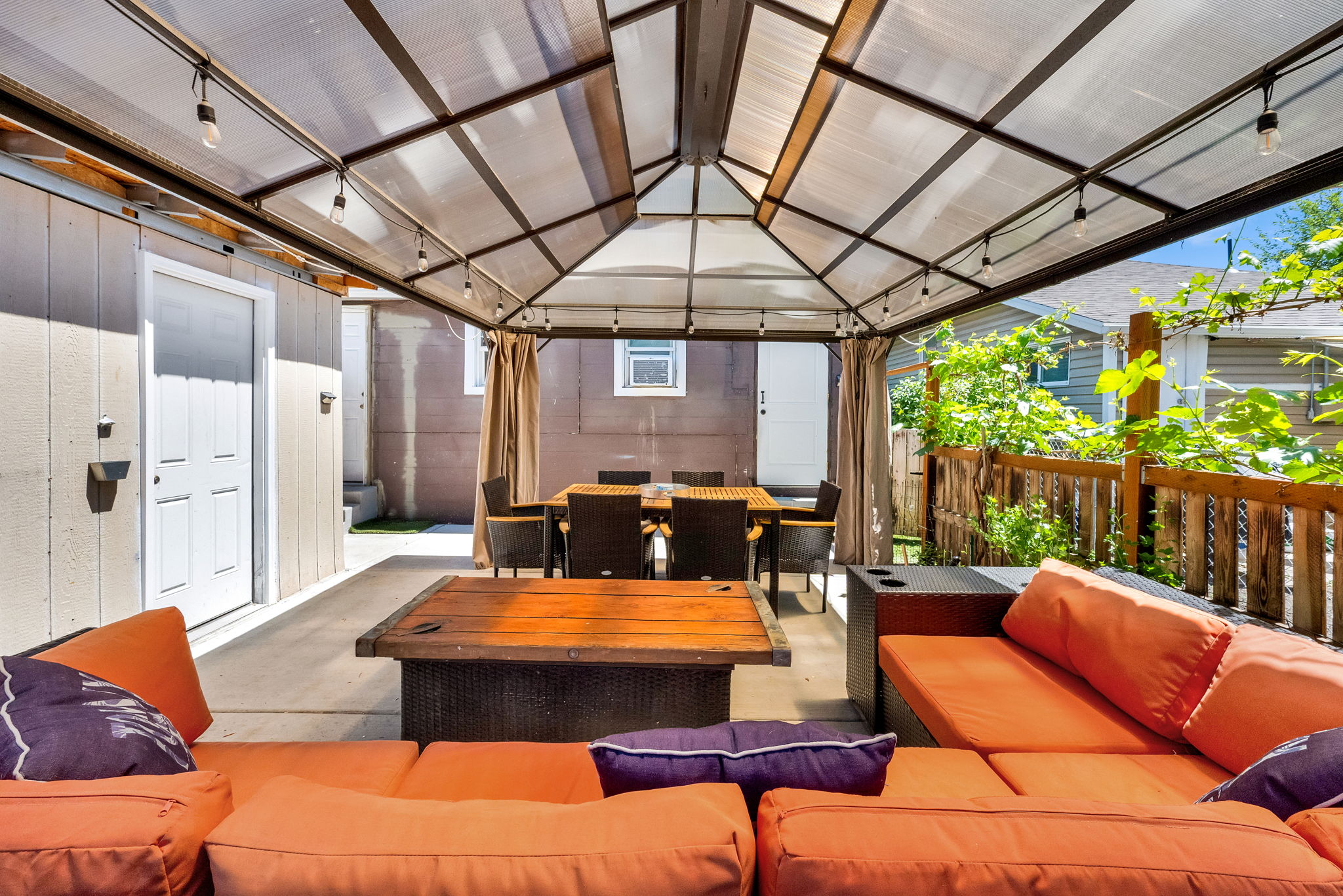 Covered patio area featuring a clear panel roof, string lighting, and concrete flooring