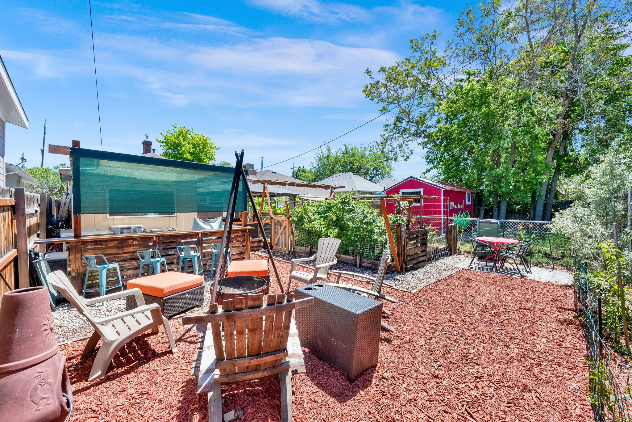 Outdoor entertainment space with a built-in bar, overhead shade structure, and a red garden shed