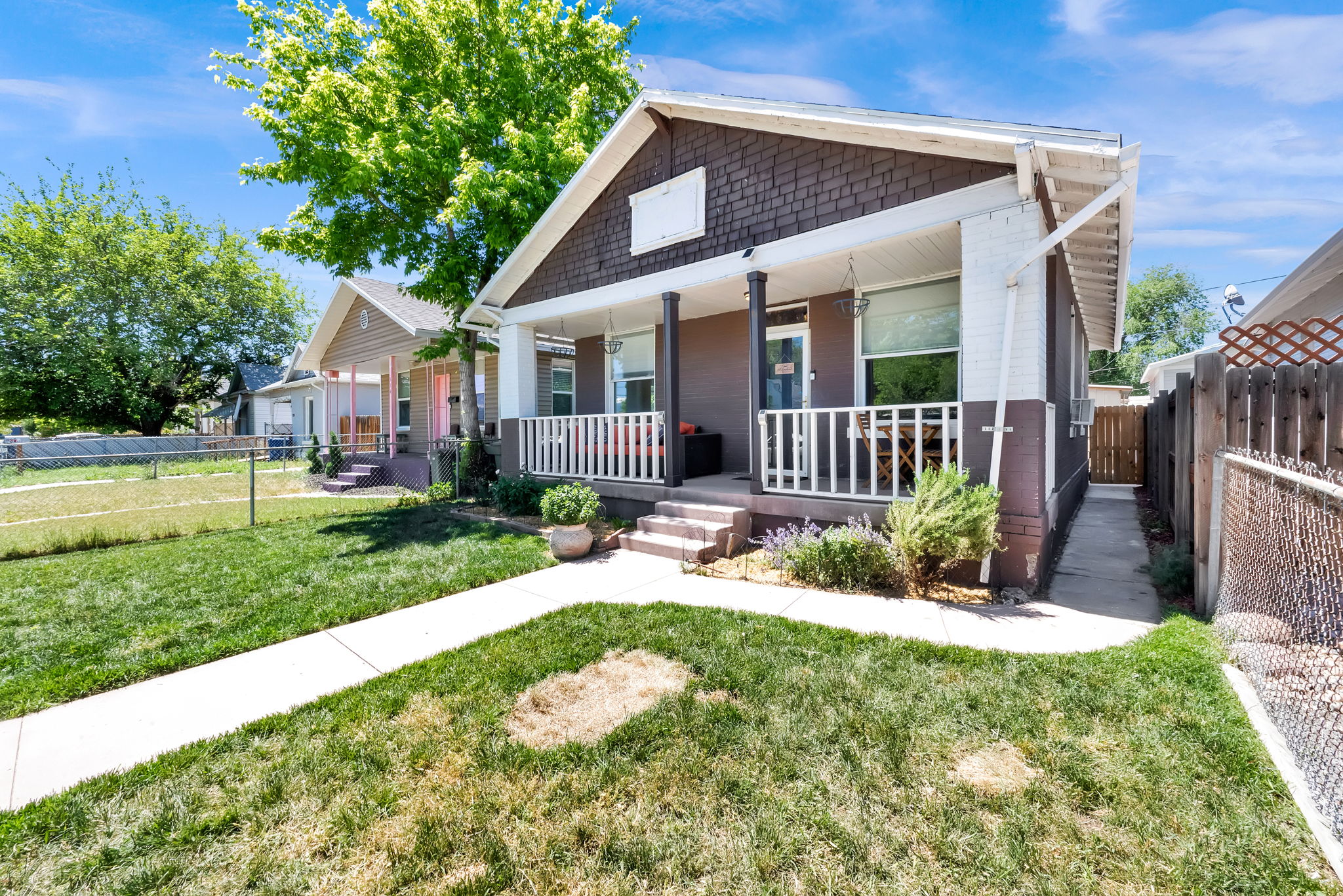 Front exterior featuring a covered porch with white railing, shake siding accent, and a paved walkway