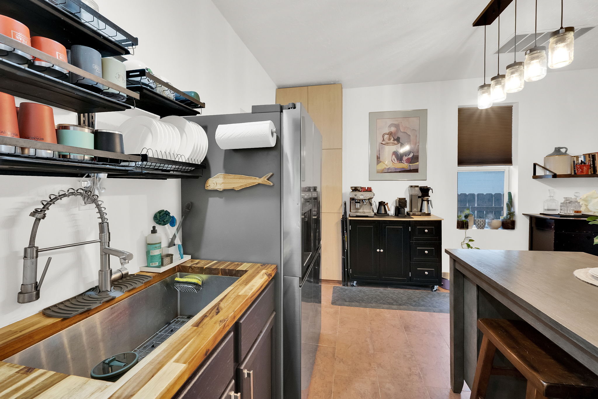 Kitchen featuring wood-finish countertops, a stainless steel sink with a high-arc faucet, and an overhead lighting fixture with multiple jar-style pendants
