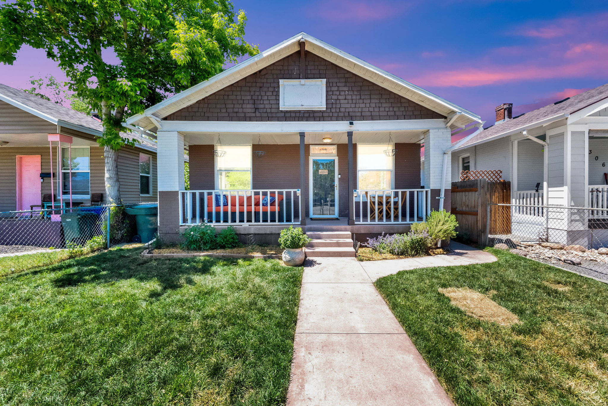 Craftsman-style home featuring a covered front porch with white railing, a wood shake gable, and a concrete walkway