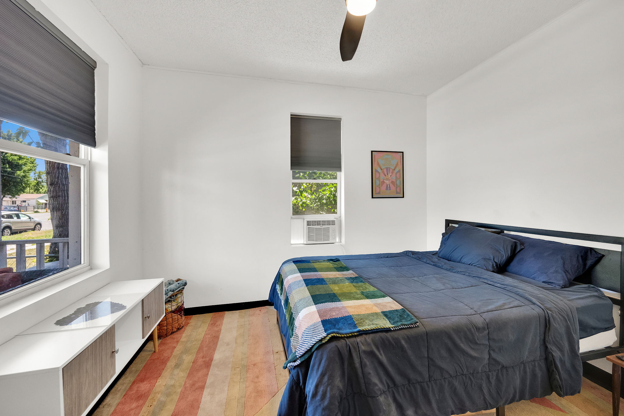 Bright room featuring patterned wood-finish flooring, white walls, and a ceiling fan