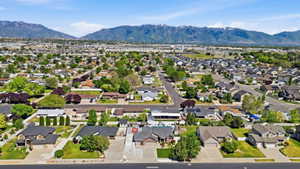 Expansive neighborhood featuring residential properties with pitched roofs, mature trees, and paved streets, set against a backdrop of distant mountains