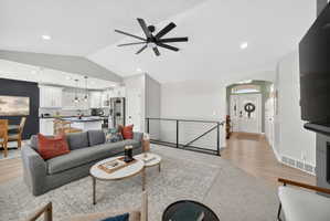 Open-concept living area featuring a vaulted ceiling with a contemporary ceiling fan, recessed lighting, and light wood-finish flooring