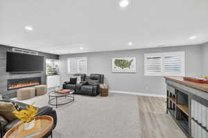 Entertainment space featuring a linear electric fireplace with a dark stone-look surround, a built-in wet bar with white cabinetry, and recessed lighting