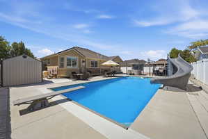 Expansive backyard featuring a rectangular in-ground pool with a diving board and slide