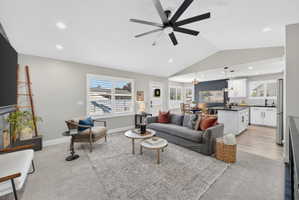 Spacious open-concept living area featuring vaulted ceilings, recessed lighting, and a modern ceiling fan