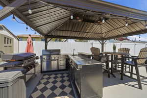 Outdoor covered patio featuring a built-in stainless steel grill, integrated countertop space, and sink