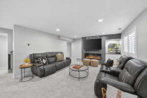 Spacious living area featuring light gray carpet, recessed lighting, and a modern entertainment wall