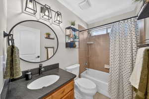 Bathroom featuring a wood-finish vanity with a dark countertop and integrated sink, a large circular mirror, and a three-light vanity fixture