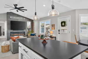 Kitchen island with a dark countertop and white cabinetry, featuring two glass pendant lights