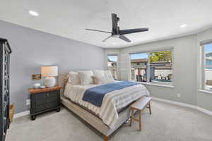Spacious bedroom featuring light gray walls, recessed lighting, and a modern ceiling fan