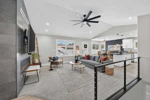 Spacious living area featuring a vaulted ceiling with an overhead fan, recessed lighting, and light-colored carpeting