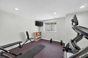 Dedicated fitness area featuring durable rubber flooring and recessed lighting