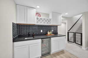 Wet bar featuring white shaker cabinetry, dark subway tile backsplash, and a built-in beverage refrigerator