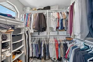 Custom closet system featuring multiple hanging rods, integrated shelving units, and an angled window for natural light