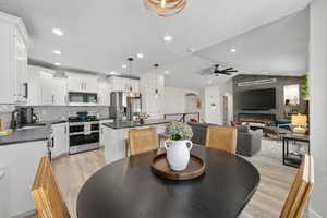 Open-concept living space featuring a modern kitchen with white cabinetry, stainless steel appliances, and a tiled backsplash