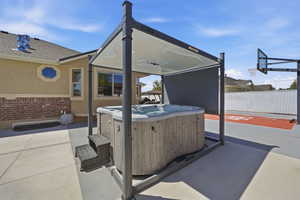 Outdoor spa with a protective pergola, positioned on a concrete patio