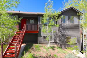 Dark gray horizontal siding exterior with a bright red entry door and a matching red exterior staircase