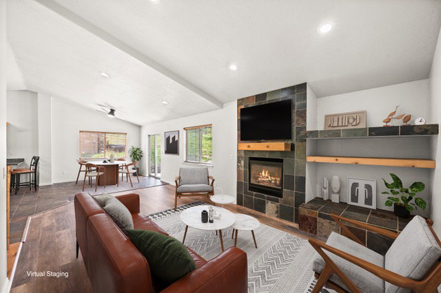 Living space featuring a slate-tiled fireplace with a wood mantle, built-in shelving, vaulted ceilings, recessed lighting, and wood-finish flooring
