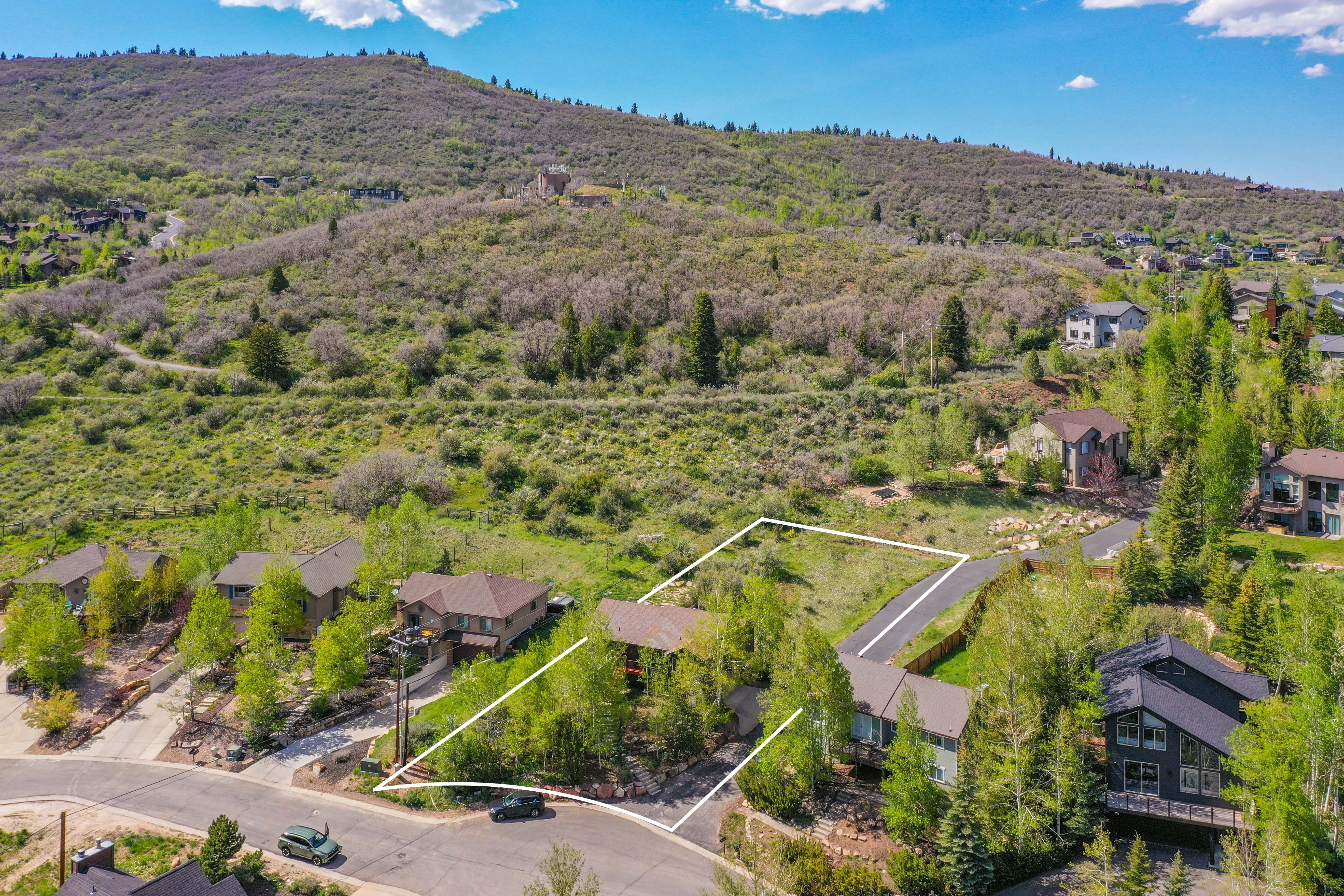 Expansive lot featuring a cleared building site, existing driveway access, and mature trees