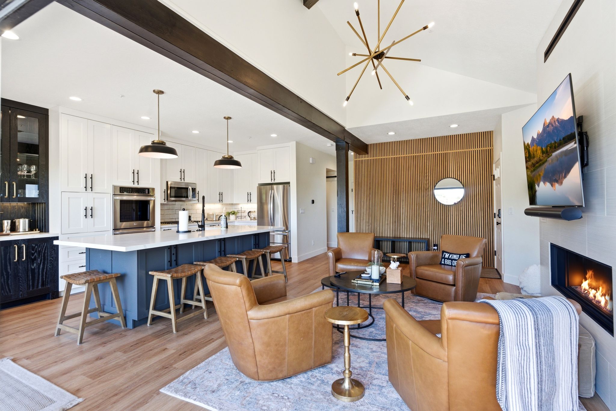 Open concept living space featuring wood-finish flooring, a vaulted ceiling, and exposed dark wood beams
