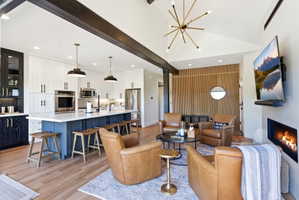 Open concept living space featuring wood-finish flooring, a vaulted ceiling, and exposed dark wood beams